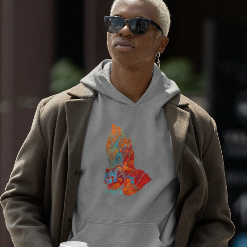 Young man wearing a grey hoodie and jogger set from the pray collection walking on a city block holding a cup of coffee